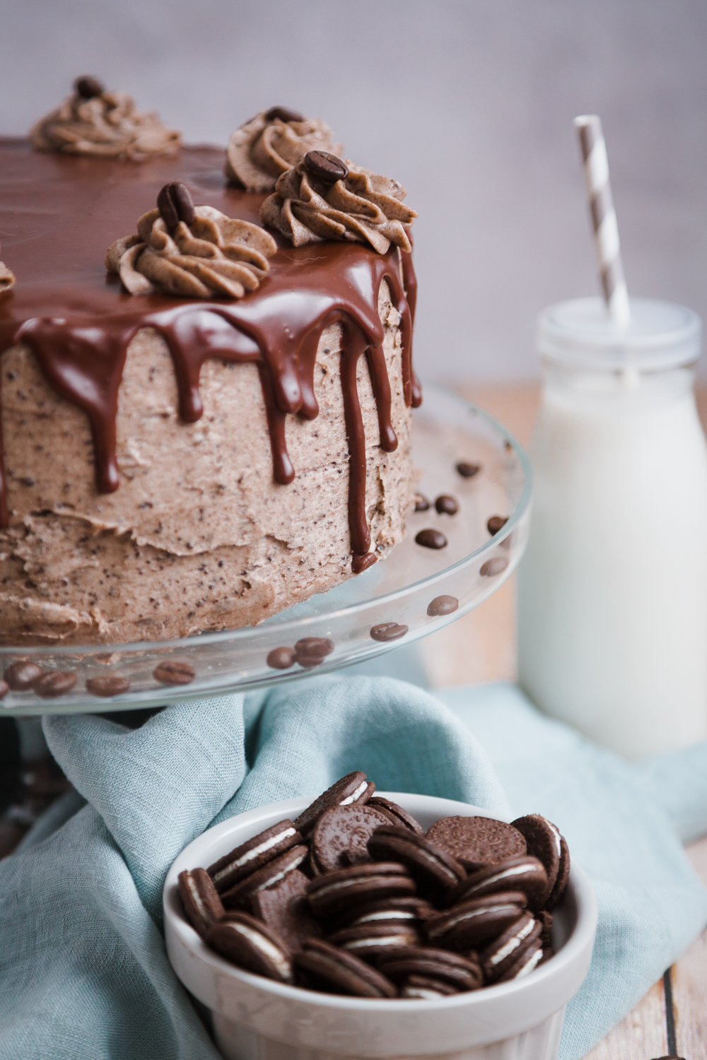 Cookie and cream cake on a cake stand with blue napkin and bottle of milk