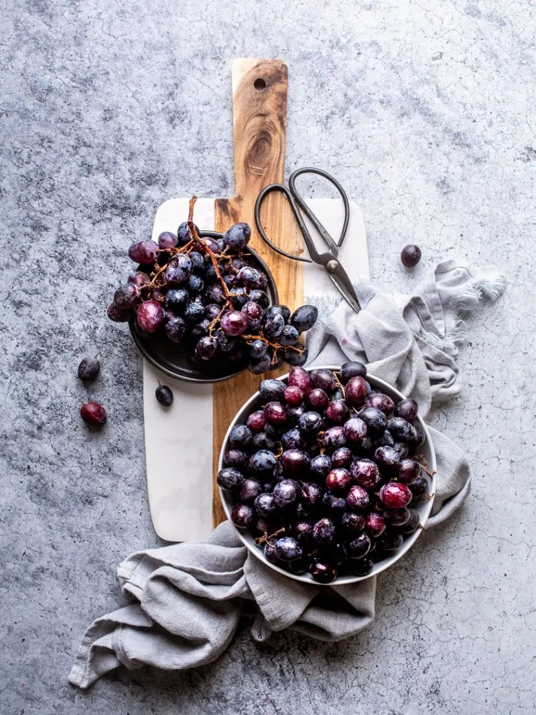 Grapes and a cutting board on a marble countertop - Food Photography by Frenchly Photography